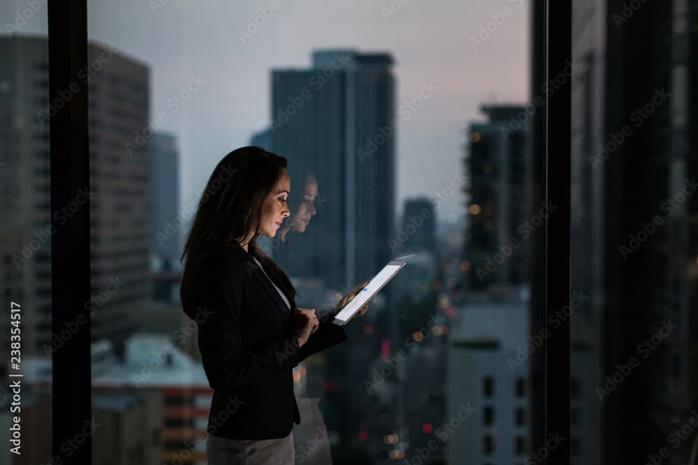 Institutional professional reviewing data on a tablet by office window